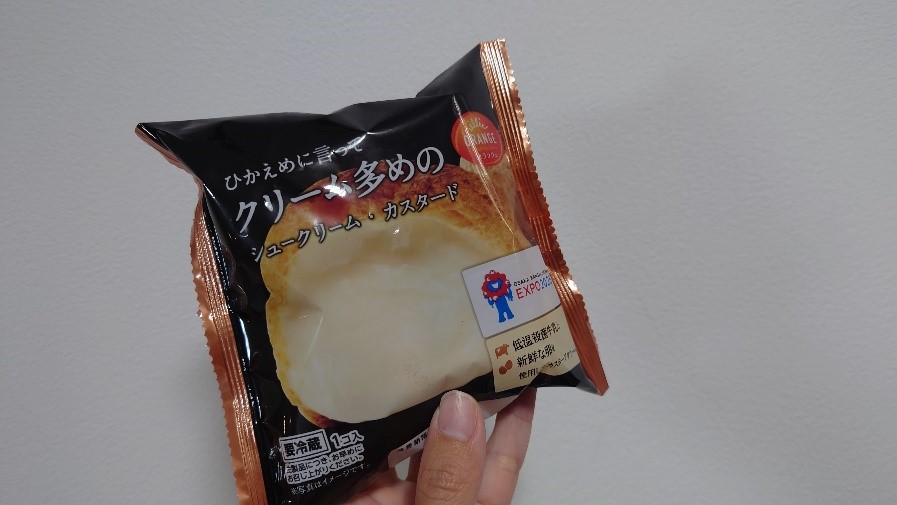 「クリーム多めのシュークリーム・カスタード」と書かれたパッケージを手に持っている様子