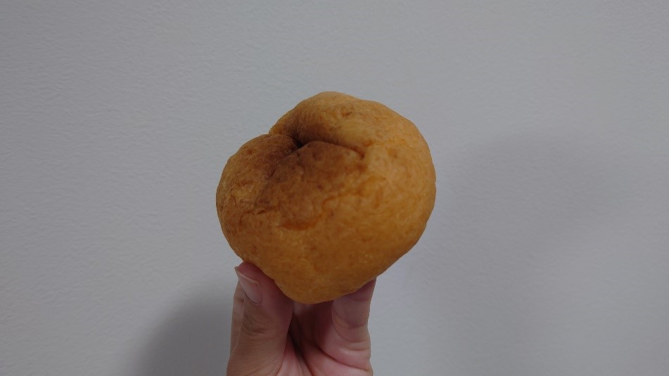 手に持たれた焼き色のついたふわふわのシュークリーム