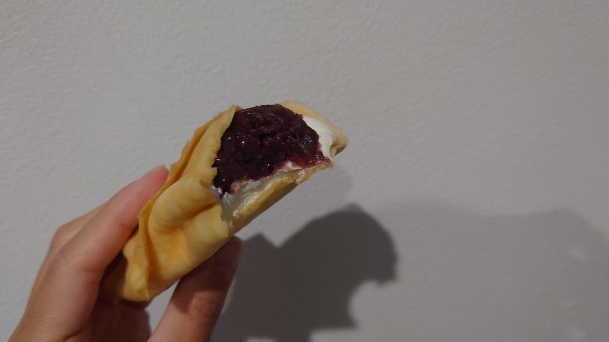 ひと口かじられたクレープの断面に、あんことホイップクリームがバランスよく詰まっている様子。