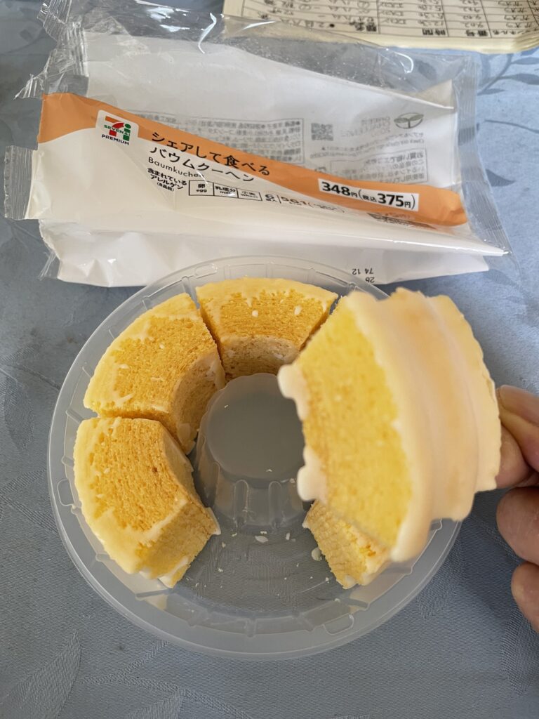 「シェアして食べるバウムクーヘン」のパッケージと、手に持った1切れのバウムクーヘン