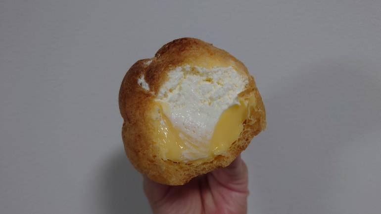 セブンイレブンのダブルシューを手に持ち、断面のクリームたっぷりの中身が見えている。