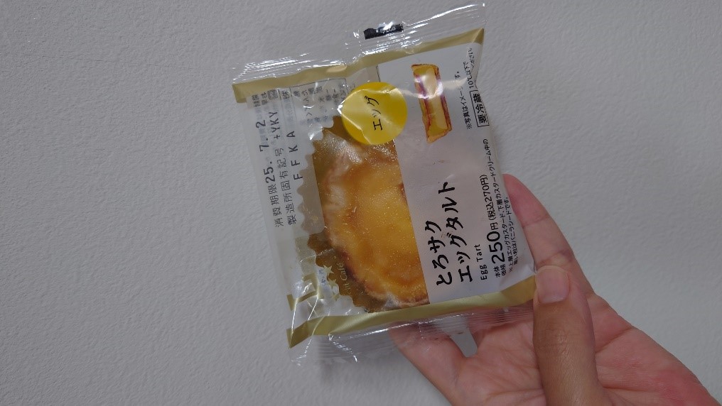 手に持たれた「とろサクエッグタルト」のパッケージ。商品名や価格などの情報が印字されている。