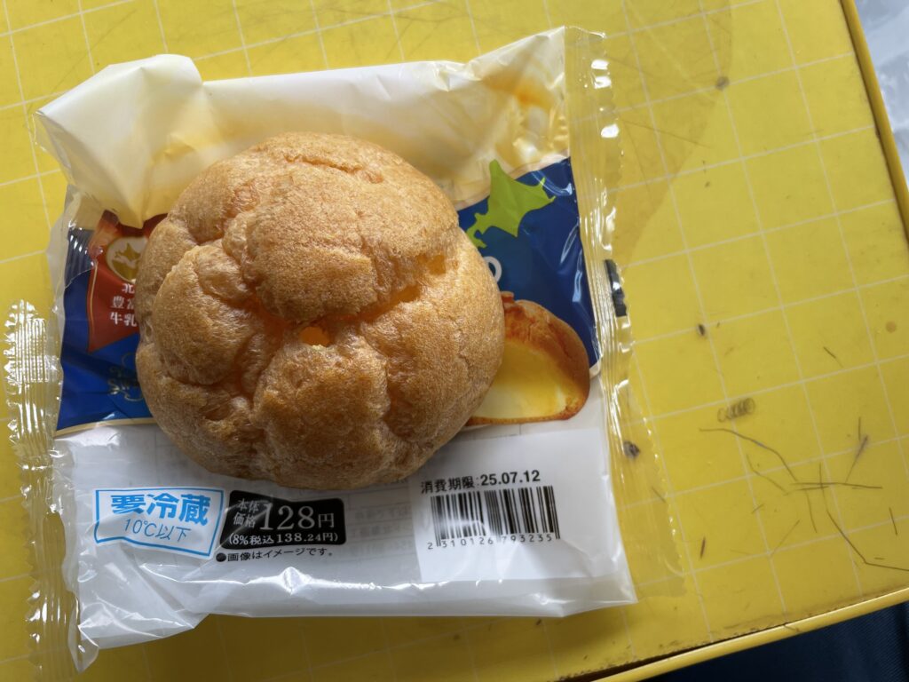 北海道産牛乳を使用したカスタードシュークリームが、パッケージの上に置かれている様子。ふっくらとした焼き色のシュー生地が特徴。