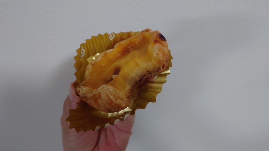 ひとくちかじられたエッグタルト。断面からはカスタードのなめらかさとパイ生地の層が見える。