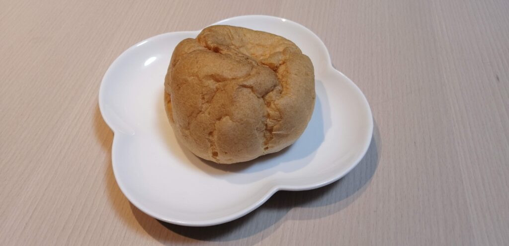 白い花形のお皿に盛られたヤマザキの「大きなシュークリーム」の中身。焼き色がついたしっとりとしたシュー皮が特徴。