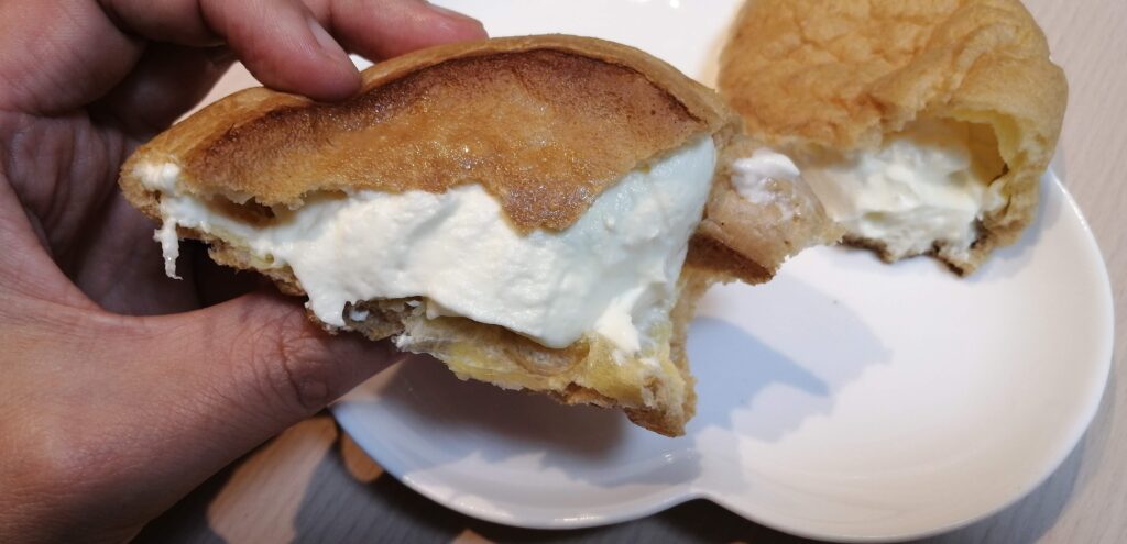 手に持ったヤマザキの「大きなシュークリーム」の断面。中にはホイップカスタードクリームがぎっしりと詰まっている。