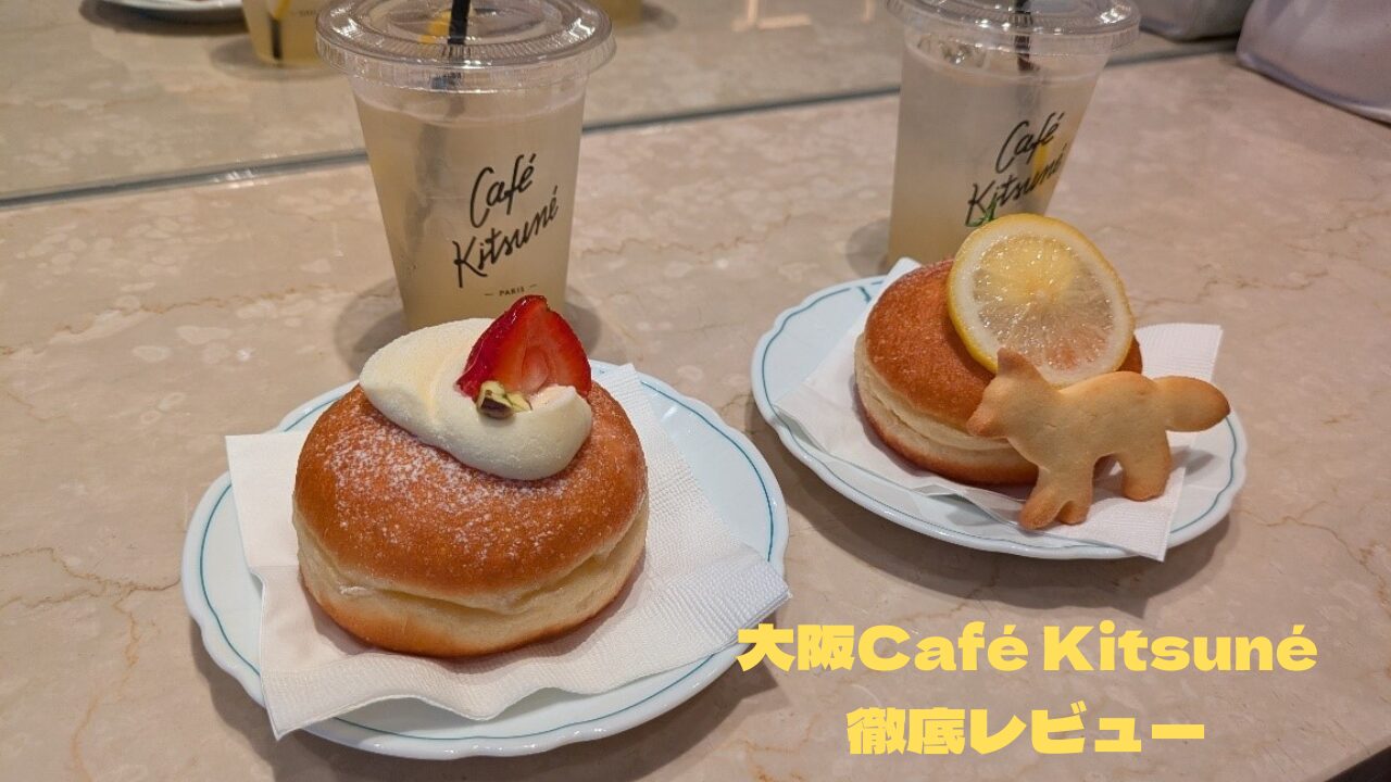 大阪の「カフェ キツネ」のテーブルに置かれたドーナツとレモネード。手前にはイチゴと生クリームがトッピングされたドーナツ、奥にはキツネのサブレとレモンが乗ったドーナツがある。背景には鏡に映る店内の様子が見える。