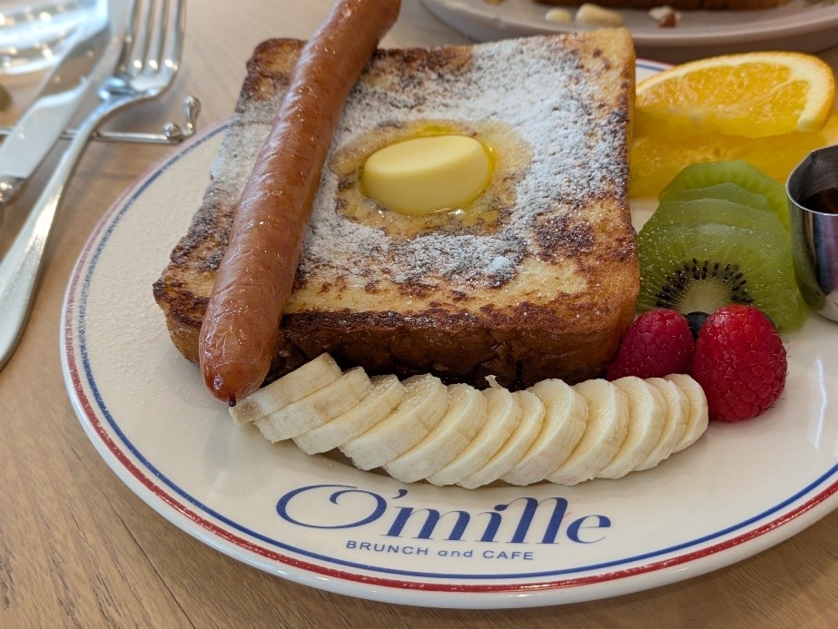フレンチトーストにバター、ソーセージ、フルーツを添えたO’milleカフェのブランチプレート