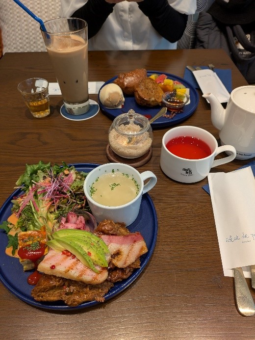 テーブルの上に並んだカフェランチセット。アボカドとベーコンのプレート、スープ、紅茶、デザート、アイスコーヒーなどが並んでいる。
